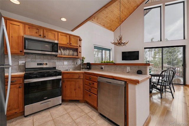507 Gcr 4980, Grand Lake, CO 80447 - kitchen featuring stainless steel appliances, a sink, a peninsula, tile counters, and brown cabinetry