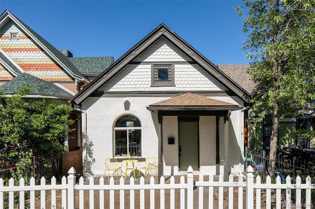 321 Fox St, Denver, CO 80223 - victorian house featuring roof with shingles, covered porch, stucco siding, and a fenced front yard