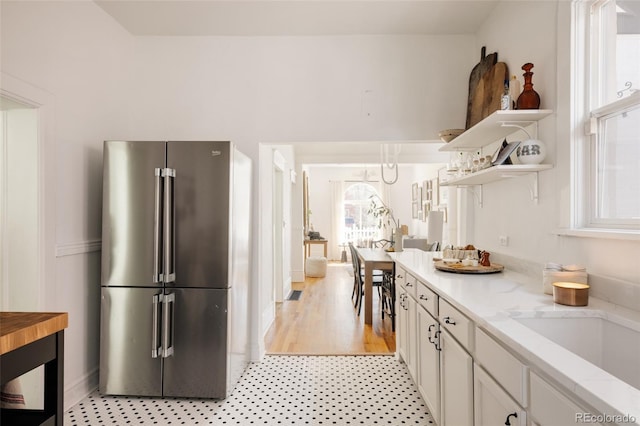 321 Fox St, Denver, CO 80223 - kitchen featuring freestanding refrigerator, open shelves, white cabinets, light stone countertops, and baseboards