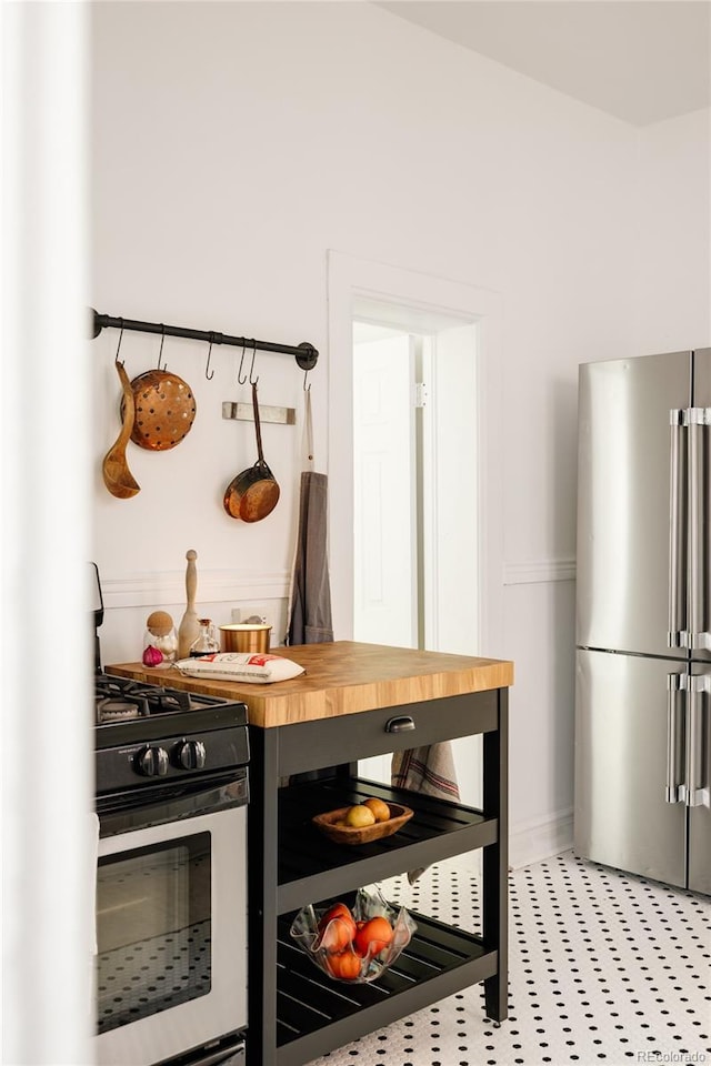 321 Fox St, Denver, CO 80223 - kitchen with appliances with stainless steel finishes, butcher block countertops, and baseboards