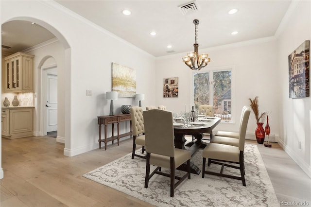 dining room with visible vents, arched walkways, crown molding, light wood-type flooring, and a notable chandelier