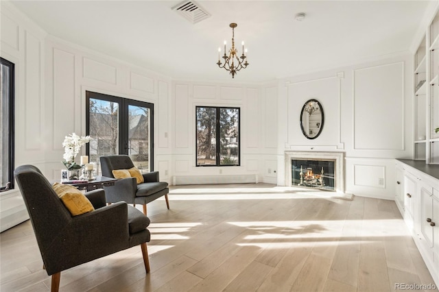 living area with a glass covered fireplace, french doors, visible vents, and a decorative wall