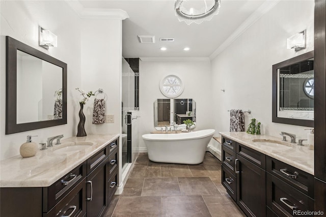 bathroom with ornamental molding, a freestanding tub, two vanities, and a sink