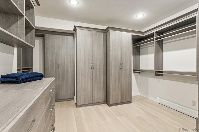 spacious closet with baseboard heating and light wood-style floors