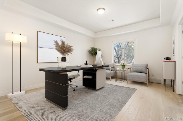 office area with a raised ceiling, visible vents, light wood-style flooring, and baseboards