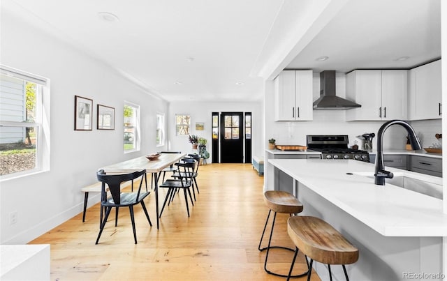 kitchen featuring wall chimney range hood, stainless steel gas stove, healthy amount of natural light, light countertops, and recessed lighting