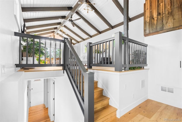 stairway with beamed ceiling, ceiling fan, wood finished floors, high vaulted ceiling, and baseboards