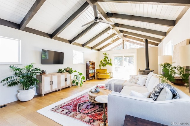 living area featuring a wood stove, light wood-style flooring, plenty of natural light, a ceiling fan, and wood ceiling