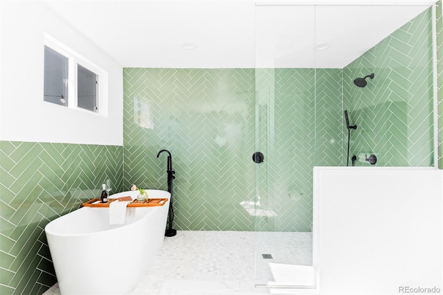 full bath with walk in shower, a soaking tub, and tile walls