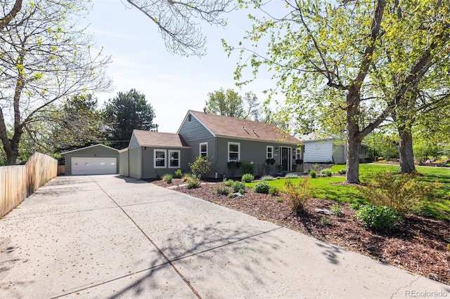 single story home with concrete driveway, a garage, fence, an outdoor structure, and stucco siding