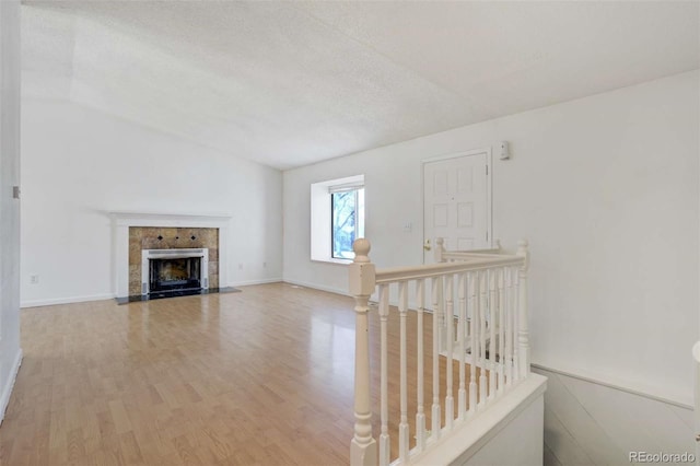 unfurnished living room with a tile fireplace, a textured ceiling, and wood finished floors