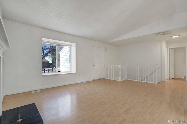 empty room featuring wood finished floors, baseboards, and visible vents