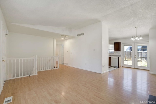 unfurnished living room with visible vents, baseboards, light wood finished floors, and an inviting chandelier