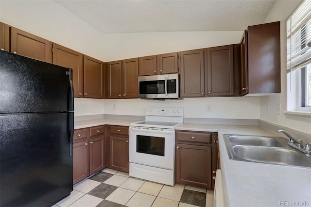 kitchen featuring freestanding refrigerator, a wealth of natural light, stainless steel microwave, a sink, and electric stove