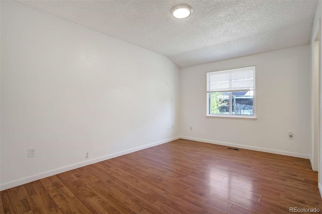 spare room featuring visible vents, a textured ceiling, baseboards, and wood finished floors