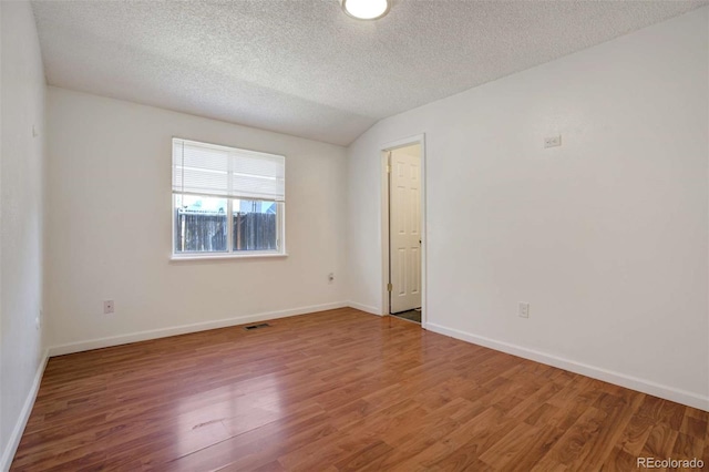 spare room featuring visible vents, baseboards, wood finished floors, and a textured ceiling