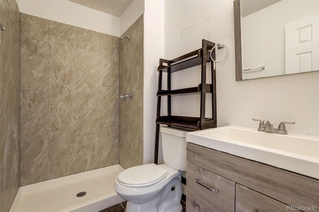 full bath with toilet, tiled shower, and vanity