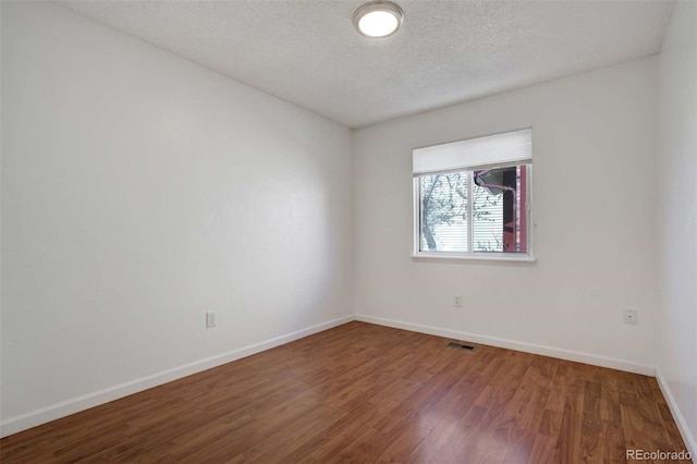 unfurnished room with visible vents, baseboards, a textured ceiling, and wood finished floors