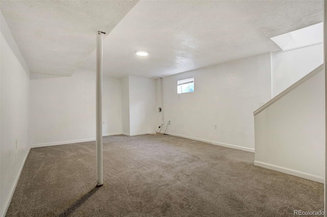 basement with carpet flooring, a textured ceiling, and baseboards