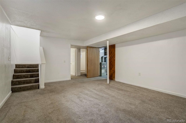 finished below grade area featuring carpet floors, baseboards, stairway, and heating unit