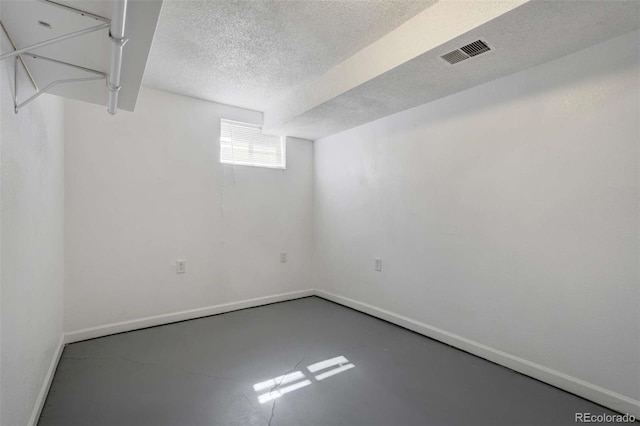 below grade area featuring a textured ceiling, baseboards, and visible vents