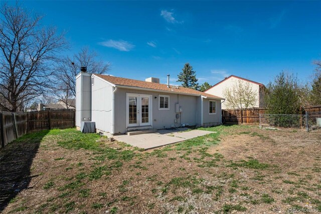 rear view of property featuring french doors, a fenced backyard, a patio, and a chimney