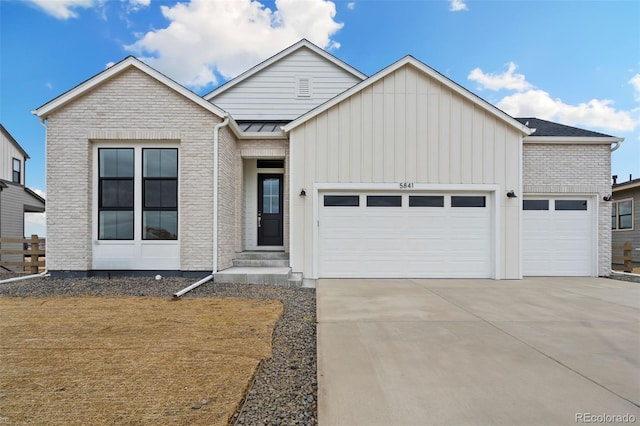 view of front of home with brick siding, driveway, a garage, and board and batten siding