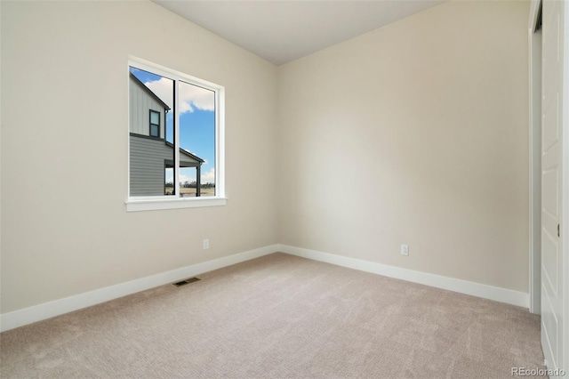 empty room featuring baseboards, visible vents, and light carpet