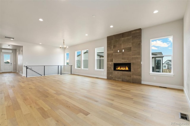 unfurnished living room with light wood-type flooring, visible vents, recessed lighting, and a tiled fireplace