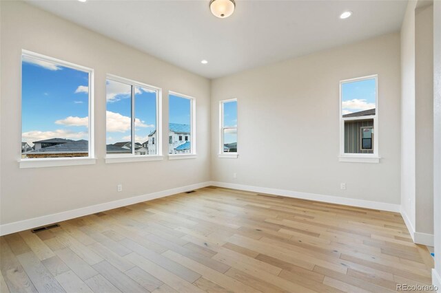 empty room featuring recessed lighting, baseboards, and light wood-style floors