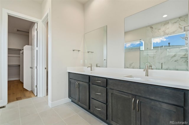 bathroom with a marble finish shower, a spacious closet, double vanity, and a sink