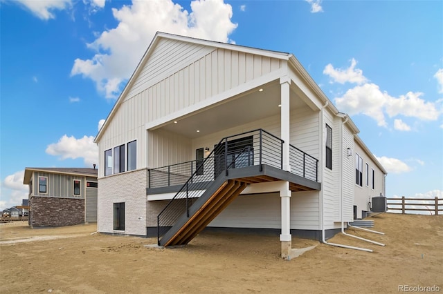 rear view of house featuring board and batten siding, central AC, and fence