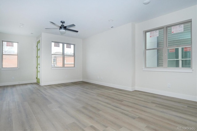 empty room featuring a wealth of natural light, ceiling fan, and light hardwood / wood-style floors