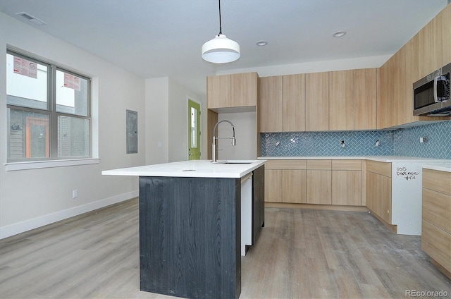 kitchen with a center island with sink, hanging light fixtures, light brown cabinets, and sink