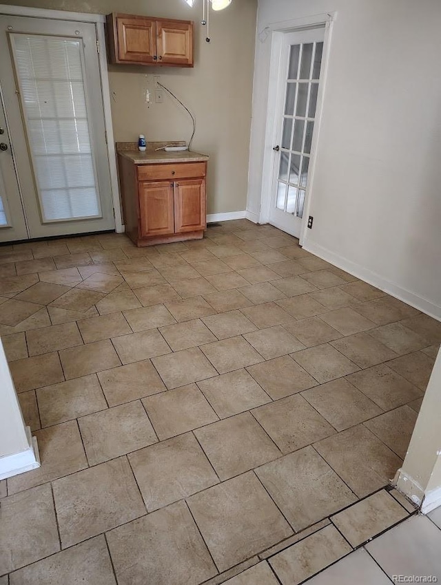 kitchen with baseboards, light tile patterned flooring, and light countertops