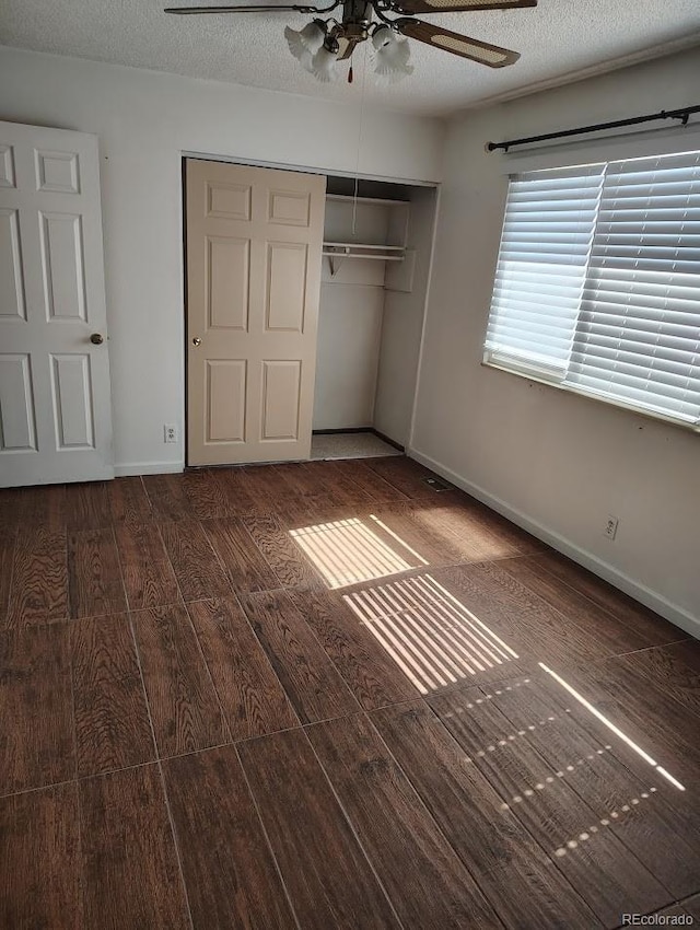 unfurnished bedroom with a closet, baseboards, a textured ceiling, and wood finished floors