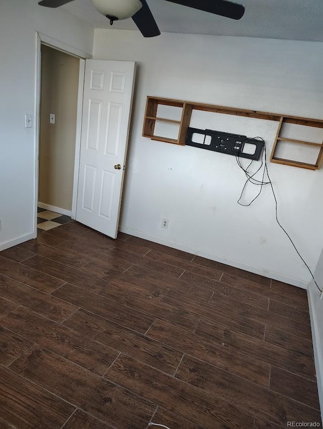 spare room featuring baseboards, dark wood-type flooring, and a ceiling fan