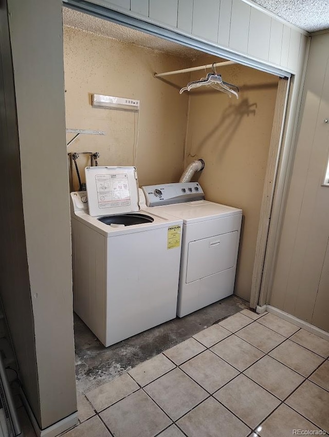 laundry room with washer and clothes dryer, laundry area, a textured ceiling, and light tile patterned floors