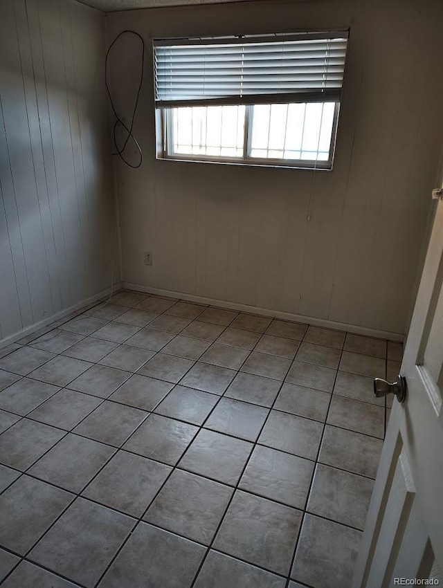 unfurnished room with light tile patterned floors and baseboards