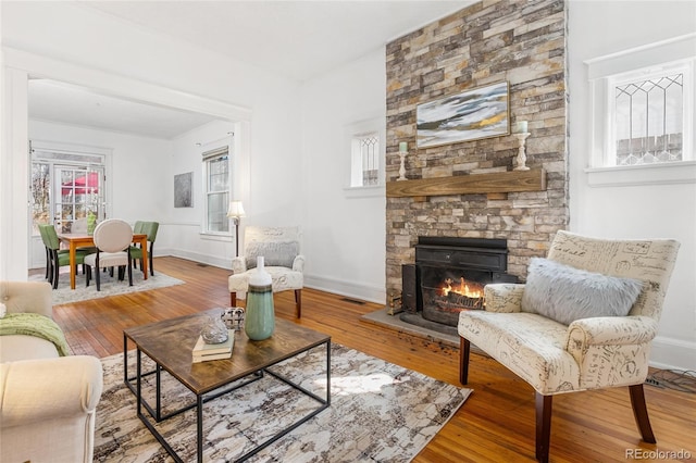 living room featuring visible vents, baseboards, a fireplace, and hardwood / wood-style flooring
