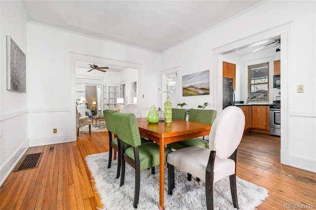 dining room with visible vents, crown molding, light wood-style flooring, and ceiling fan