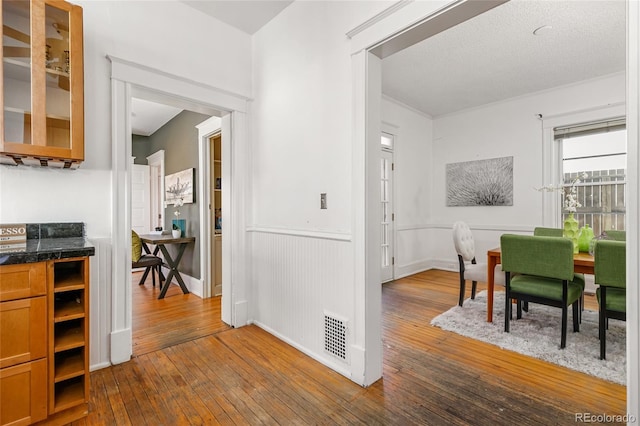 dining space with dark wood-type flooring and a wainscoted wall