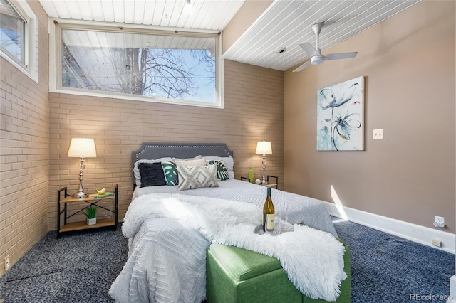 bedroom featuring baseboards, carpet flooring, ceiling fan, and brick wall
