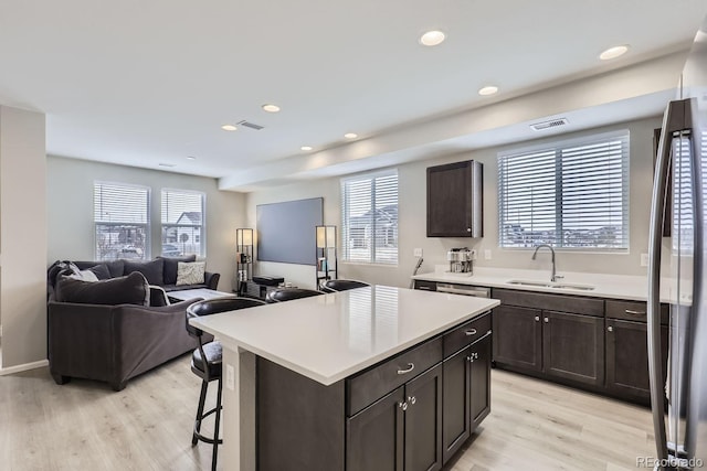 kitchen with stainless steel refrigerator, sink, a kitchen island, and light hardwood / wood-style flooring