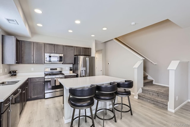 kitchen featuring visible vents, a breakfast bar, a center island, light countertops, and stainless steel appliances