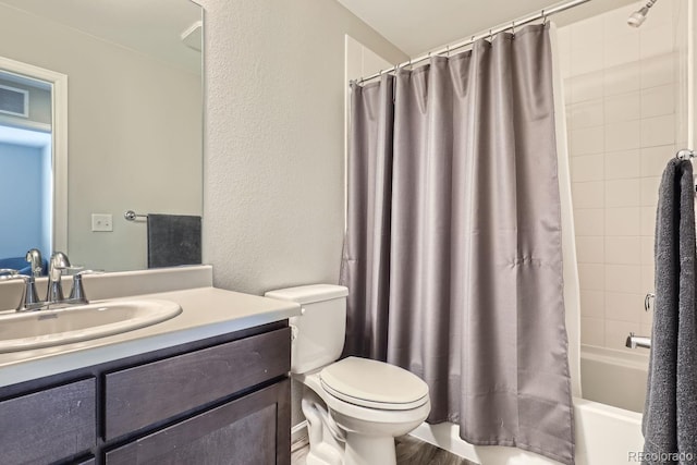 bathroom featuring a textured wall, shower / tub combo, vanity, and toilet