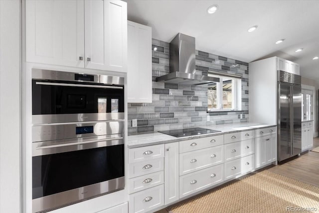 kitchen with white cabinetry, tasteful backsplash, light stone counters, stainless steel appliances, and exhaust hood