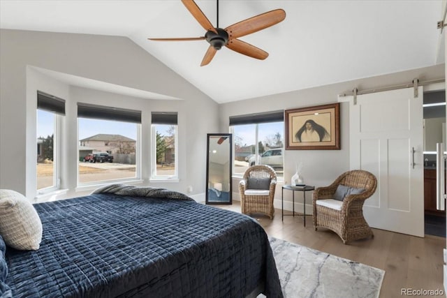 bedroom with ceiling fan, lofted ceiling, wood-type flooring, and a barn door