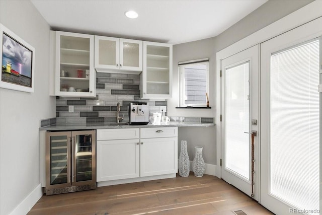 bar featuring wine cooler, white cabinetry, hardwood / wood-style floors, and decorative backsplash