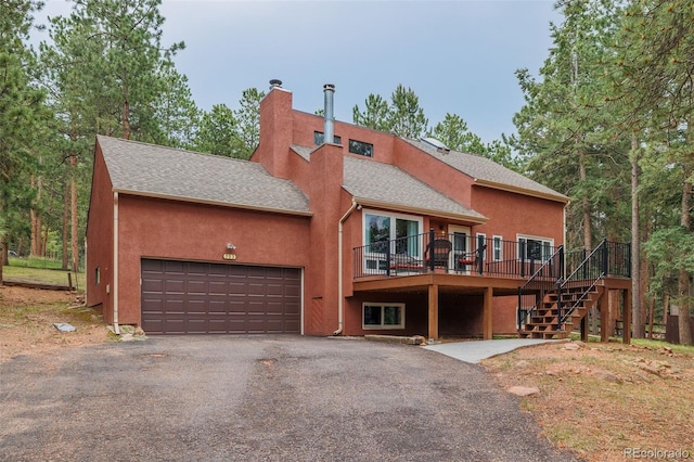 753 Edge Hill Dr, Woodland Park, CO 80863 - view of front facade featuring a shingled roof, driveway, a chimney, and stucco siding
